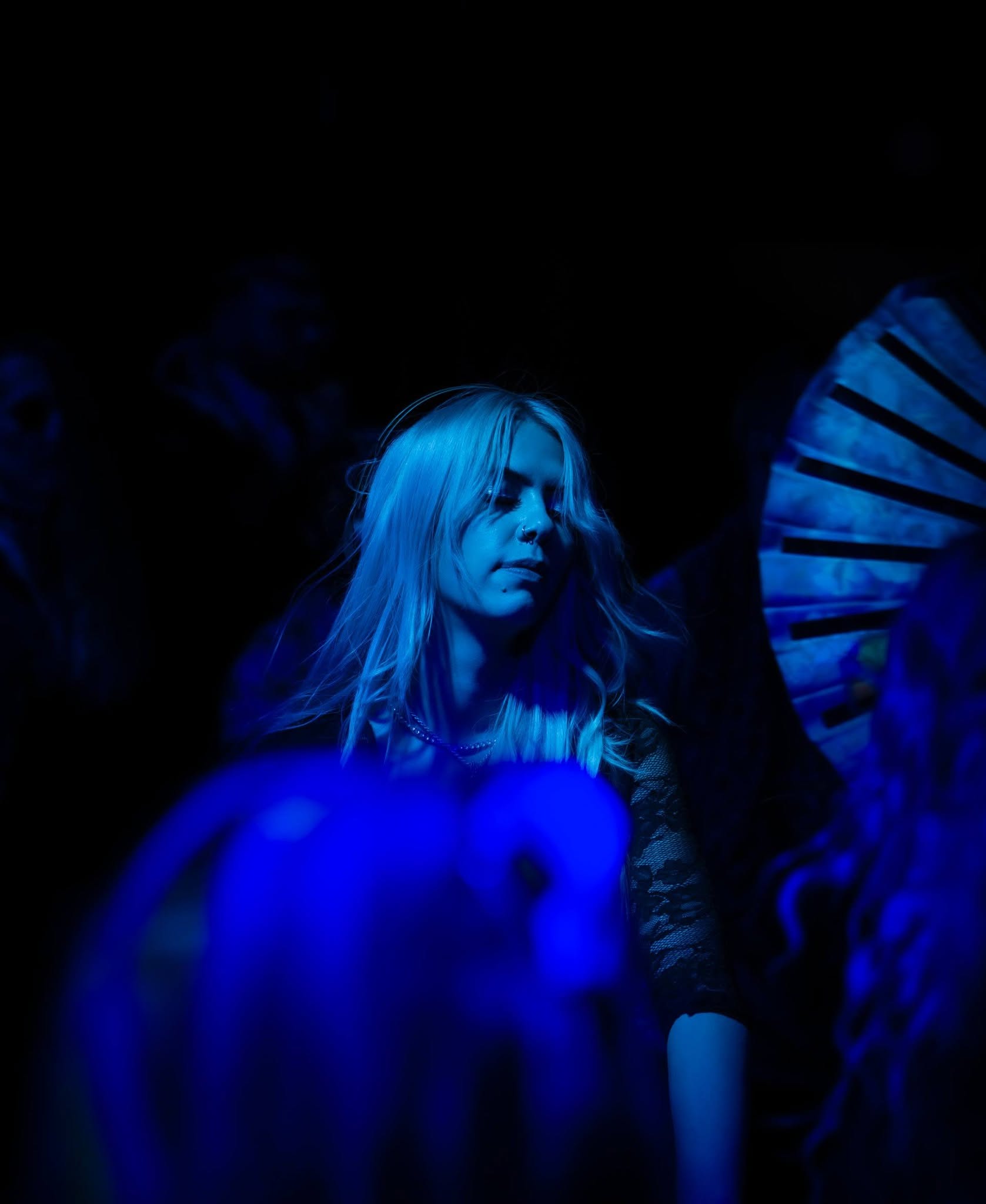 Blue-lit portrait of ROZENZA in the crowd at a nightclub